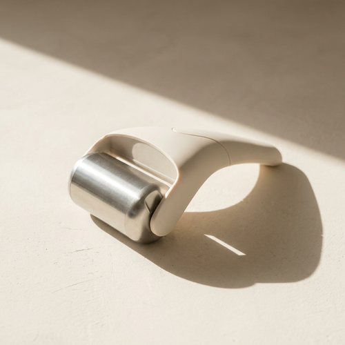 Lumi Mini Steel Ice Roller, brushed steel, on a bone plaster counter in window light