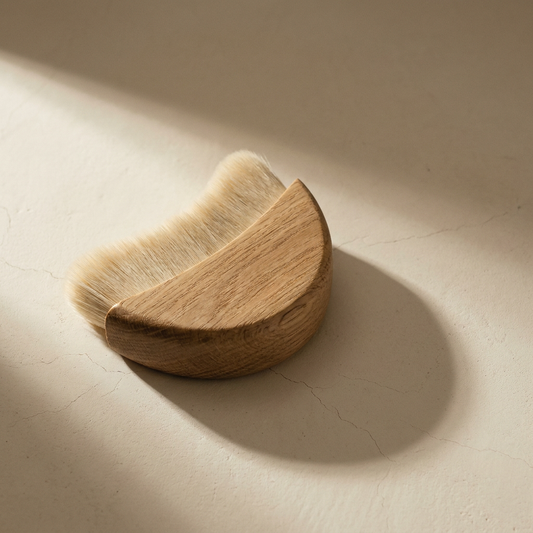 Lumi Contour Brush, oak and natural bristle, on a bone plaster counter in window light